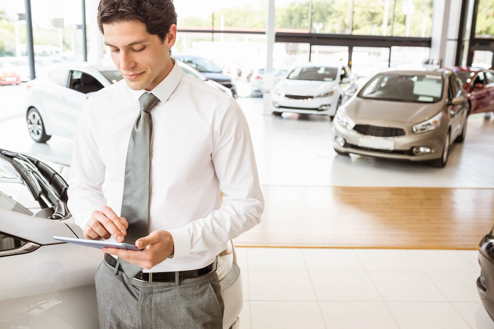 A car salesman using a tablet to manage accounts