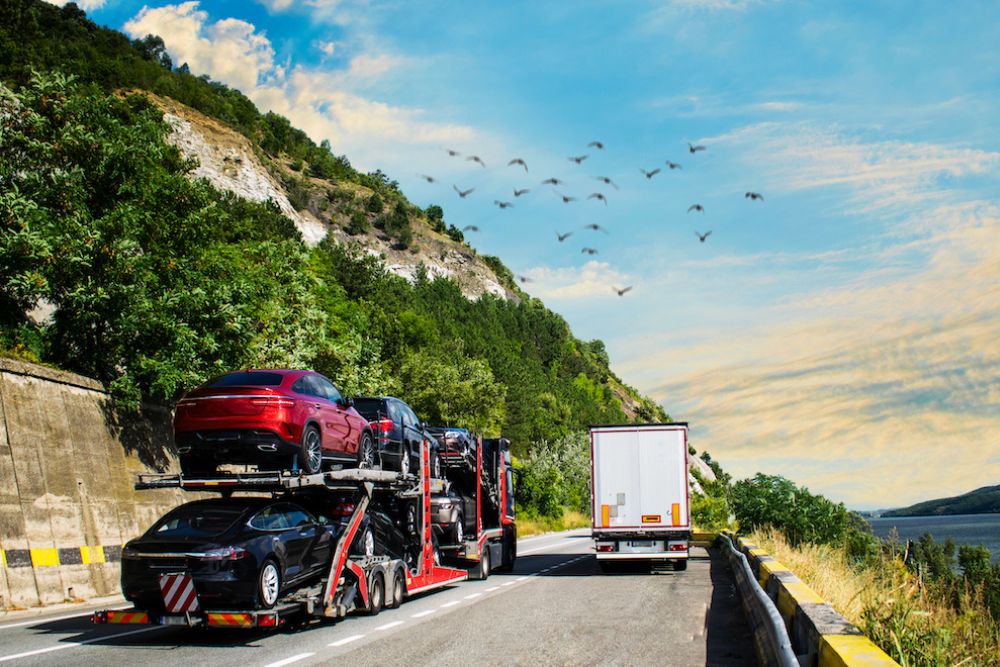An auto transport drives down a coastal highway