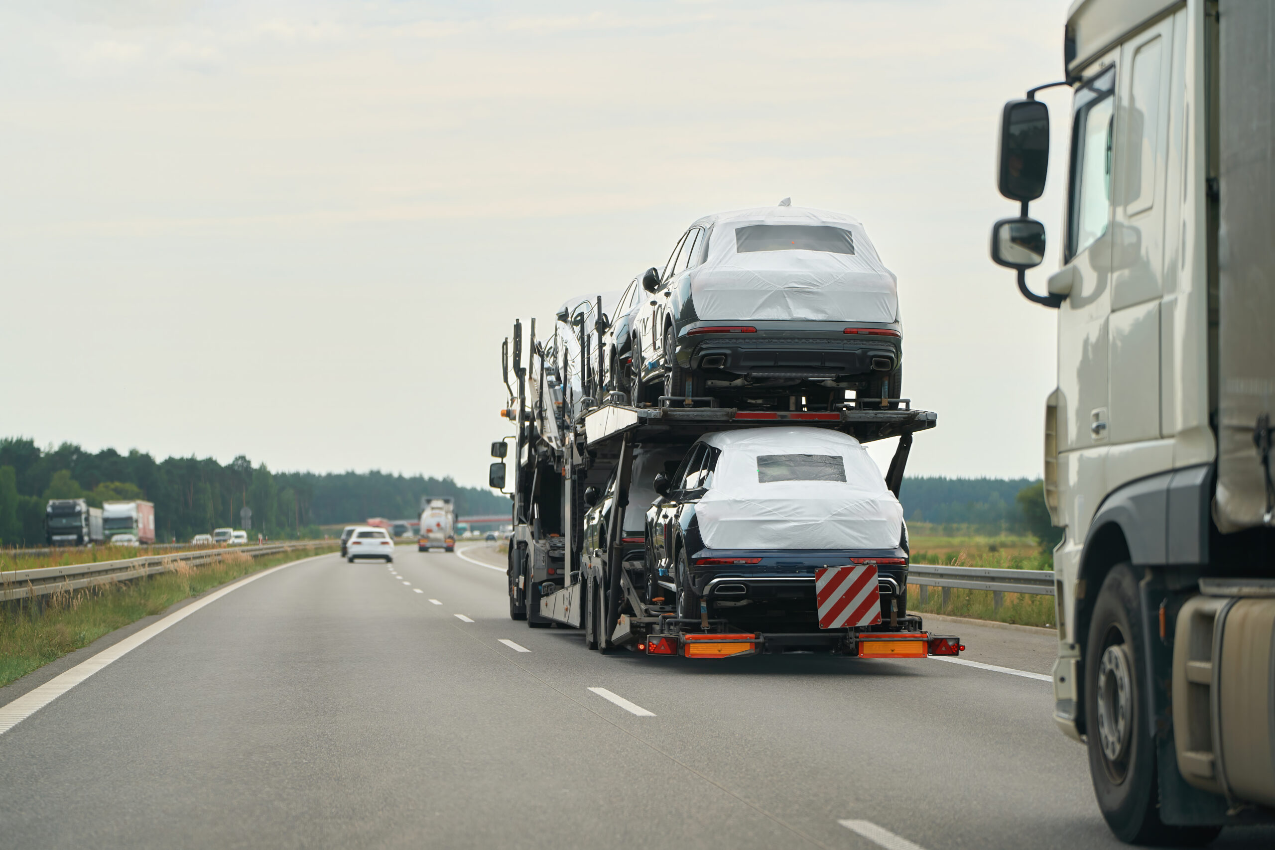 auto transport truck hauling new SUVs on highway